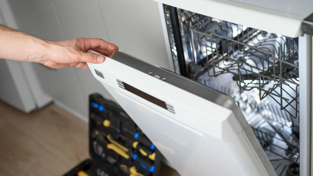 Hand holding an open dishwasher door with the inner panel visible