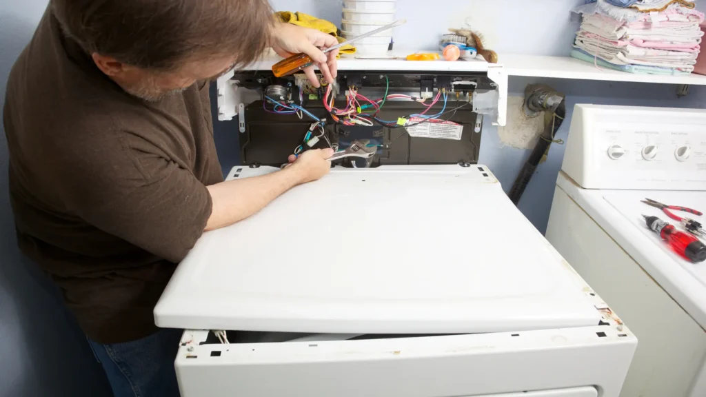Person inspecting wiring inside a dryer control console