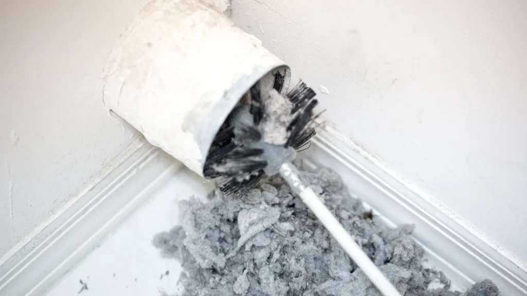 Brush and collected lint at a wall exhaust opening