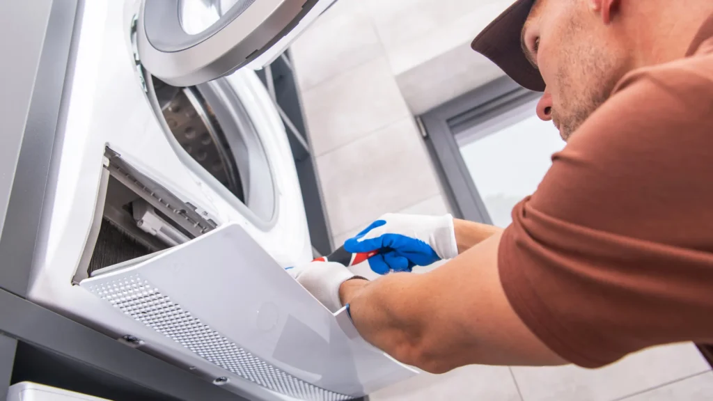 Person working beside the lower open compartment of a dryer