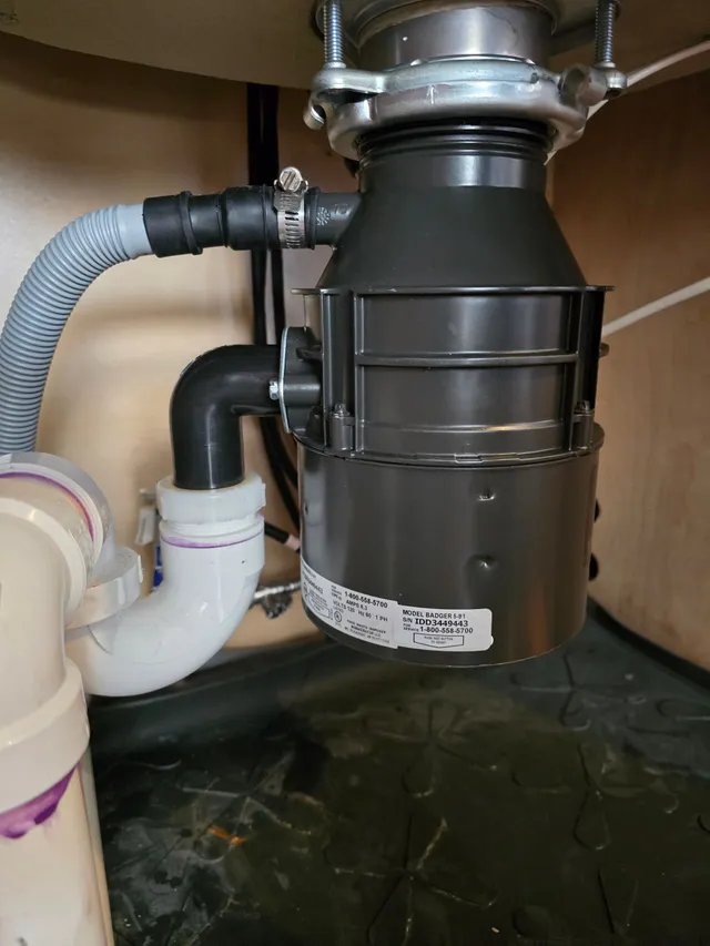 Garbage disposal beneath a sink with its drain connection visible