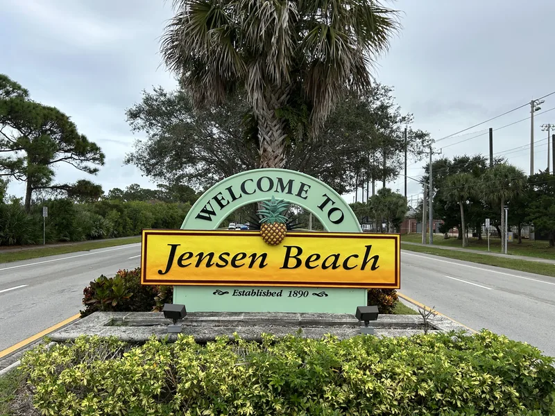 Welcome to Jensen Beach sign with palms behind it