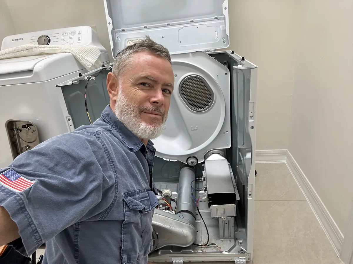 Mark beside an opened dryer with its drum removed