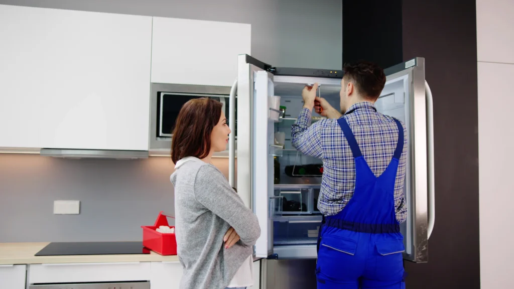 Two people beside an open refrigerator during an inspection